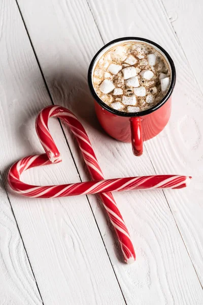愛のシンボルの形をしたクリスマスキャンディ缶の近くのココアの赤いカップ — ストック写真