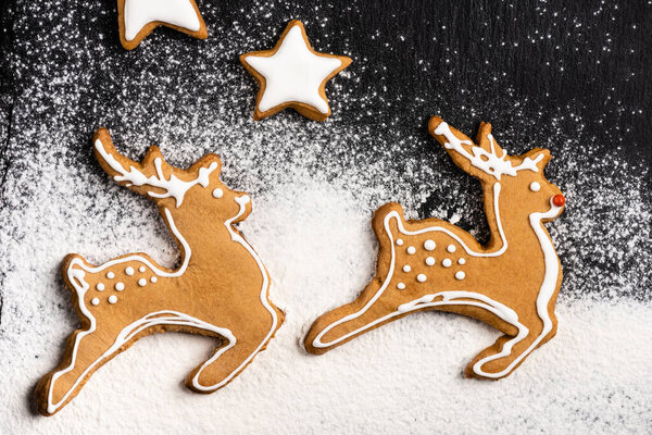 Top view of gingerbread cookies in shape of stars and deers with sugar powder