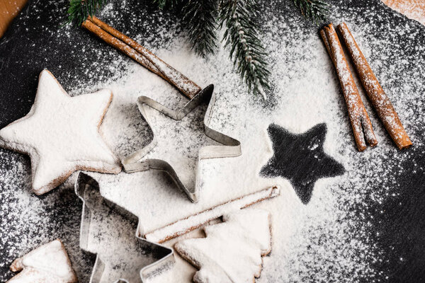 Пряничное печенье и кусачки рядом с коричными палочками и сосновой ветвью