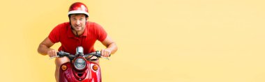 excited man in helmet riding red scooter isolated on yellow, banner clipart