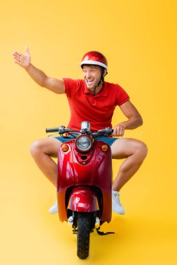 Kasklı stresli bir adam kırmızı scooter sürüyor ve sarı bir jest yapıyor.