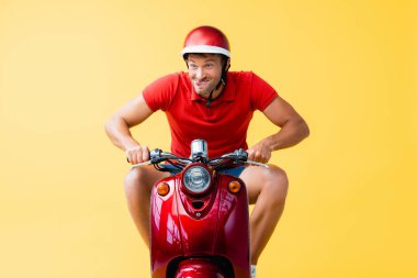 Kasklı komik bir adam kırmızı scooter sürüyor ve dili sarıya yapışıyor.