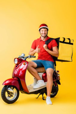 Sırt çantalı mutlu teslimatçı kırmızı scooter 'ın üzerinde oturuyor ve sarı başparmağını gösteriyor.