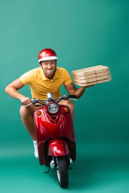 delivery man in helmet biting lips while riding scooter while holding pizza boxes on blue clipart
