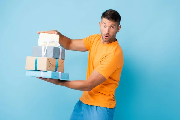 Homme Surpris Shirt Tenant Des Cadeaux Enveloppés Sur Bleu — Photo