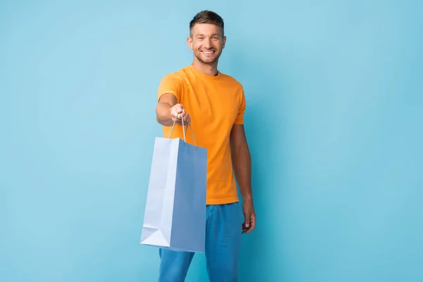 Cheerful Man Shirt Outstretched Hand Holding Shopping Bag Blue — Stock Photo, Image