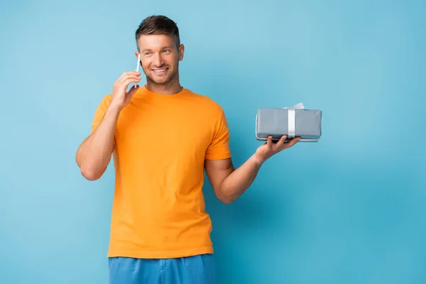 Šťastný Muž Tričku Drží Dárkovou Krabici Mluví Smartphone Modré — Stock fotografie