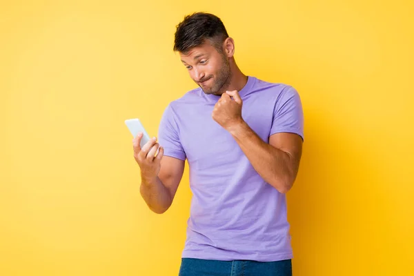 Ontevreden Man Toont Gebalde Vuist Kijken Naar Smartphone Geel — Stockfoto