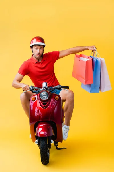 Surprised Delivery Man Helmet Riding Scooter Holding Shopping Bags Yellow — Stock Photo, Image