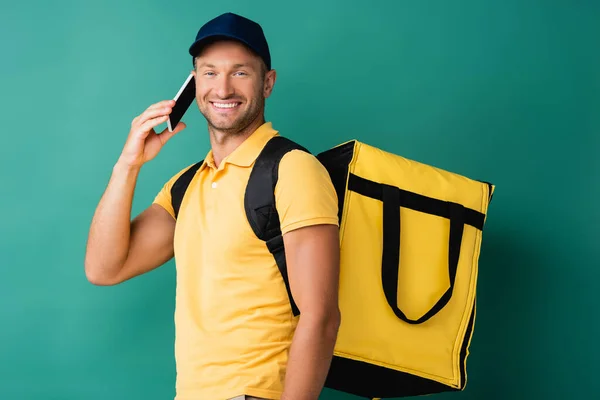 Happy Delivery Man Μεταφέρουν Κίτρινο Σακίδιο Και Μιλώντας Στο Smartphone — Φωτογραφία Αρχείου