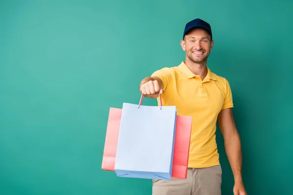 Cheerful Delivery Man Outstretched Hand Carrying Shopping Bags Blue — Stock Photo, Image