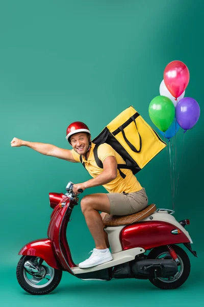 Cheerful Delivery Man Backpack Outstretched Hand Riding Scooter Balloons Blue — Stock Photo, Image