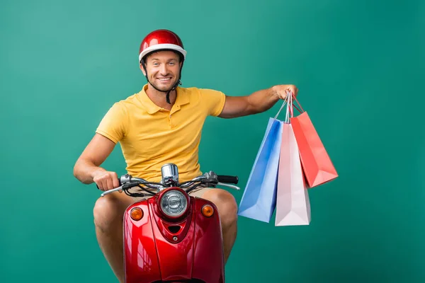 Happy Delivery Man Helmet Riding Scooter While Holding Shopping Bags — Stock Photo, Image
