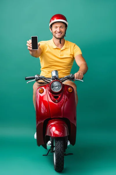 Pria Pengiriman Bahagia Dalam Helm Mengendarai Skuter Sambil Memegang Smartphone — Stok Foto