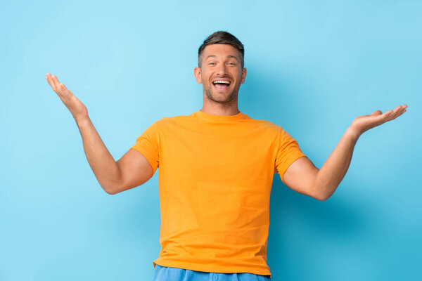 excited man in yellow t-shirt gesturing on blue