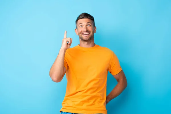 Vrolijk Man Geel Shirt Wijzend Met Vinger Terwijl Omhoog Kijkend — Stockfoto