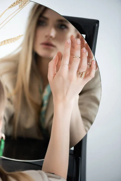 前景がぼやけた丸い鏡に触れる女性の姿を — ストック写真