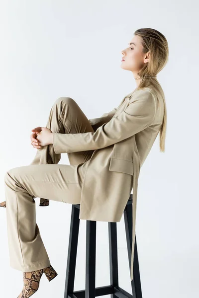 坐在白色背景的凳子上穿着西服的年轻模特简况 — 图库照片
