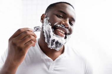 Afro-Amerikan mutlu bir adamın traş olurken sakalını tıraş edişinin portresi. 
