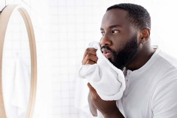 afro-american man drying beard with towel 