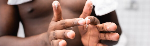 панорамный снимок афро-американского мужчины, использующего лекарство для укрепления роста бороды