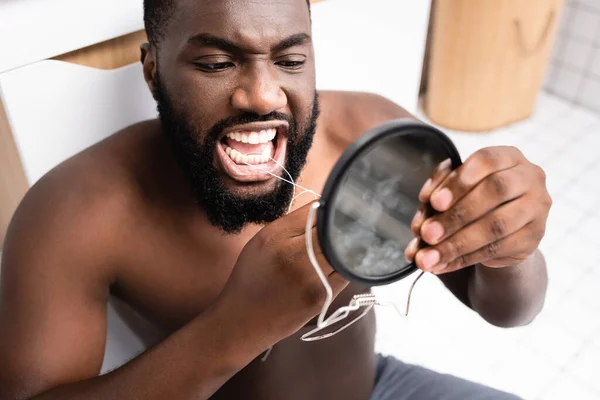 Hombre Afroamericano Sentado Mirando Espejo Pequeño Usando Hilo Dental —  Fotos de Stock