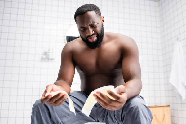 confused afro-american man trying wax strips