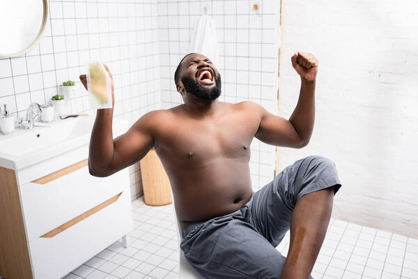 afro-american man tearing off wax strips and screaming from pain 