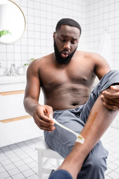 Afro American Man Tearing Wax Strips Leg — Stock Photo, Image