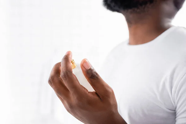 stock image cropped view of afro-american man in white t-shirt using perfume 