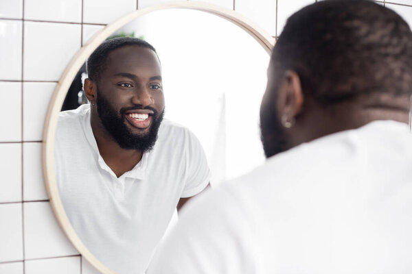 smiling afro-american man looking in mirror