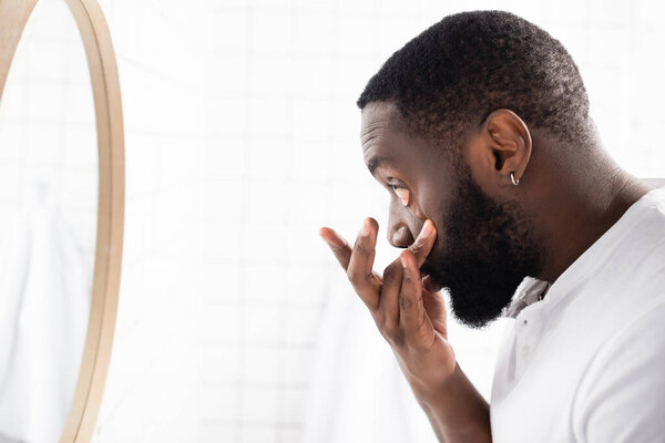 side view of afro-american man pulling lower eyelid with fingers