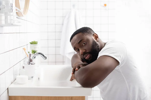 Afroamerikanischer Mann Lehnt Sich Auf Waschbecken Und Blickt Kamera — Stockfoto