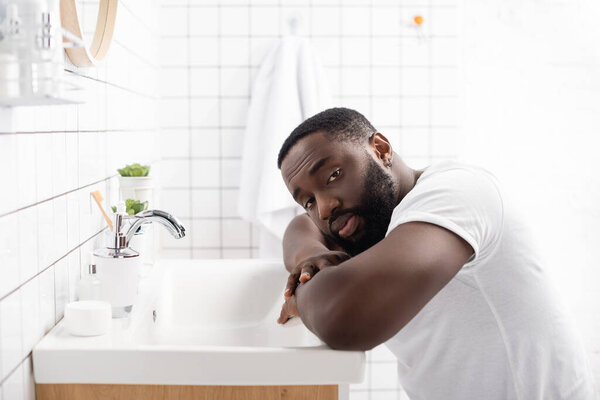 afro-american man leaning on sink and looking at camera