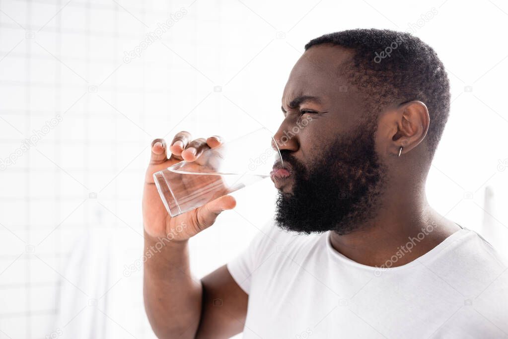 afro-american man grimacing and drinking water