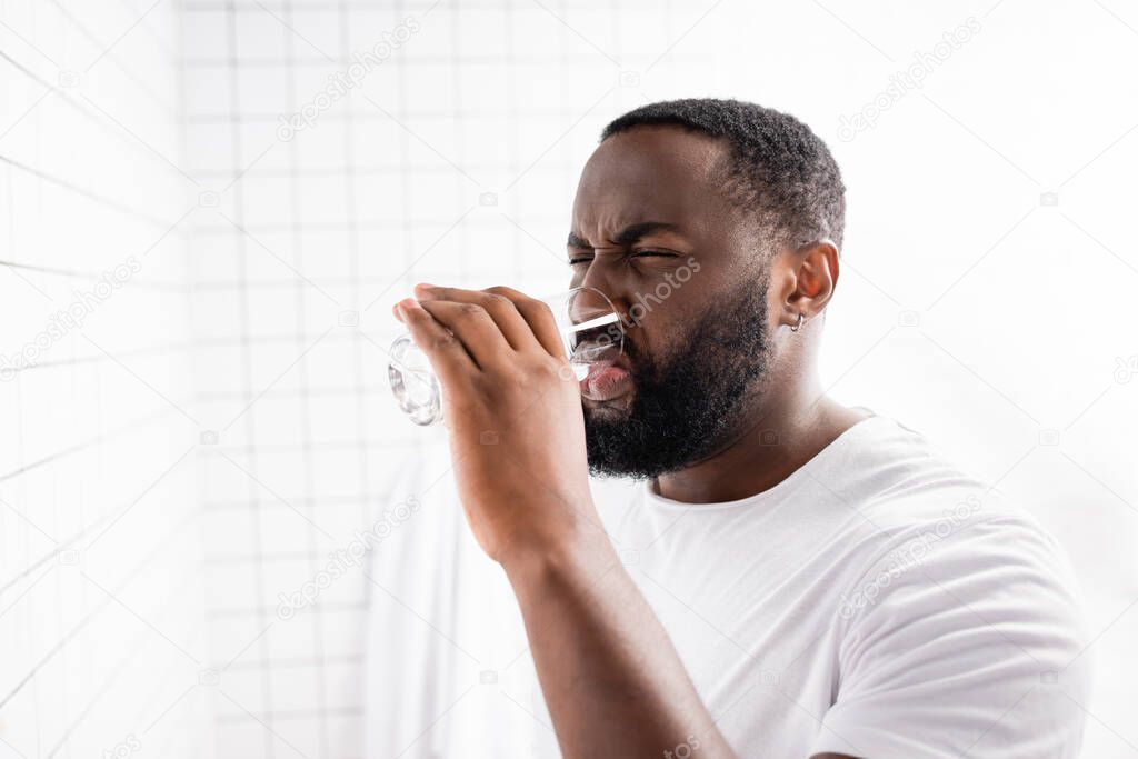 afro-american man grimacing and drinking water