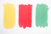 top view of abstract colorful green, yellow and red paint brushstrokes on white background