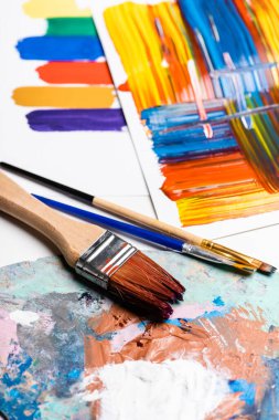 paintbrushes and abstract colorful brushstrokes on paper on white background clipart