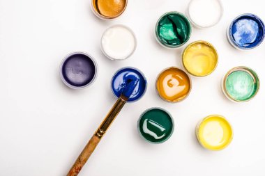 Beyaz arkaplanda Gouache boya ve boya fırçalarının üst görünümü