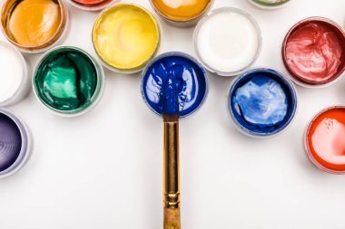 Beyaz arkaplanda renkli Gouache boyaları ve boya fırçalarının üst görünümü