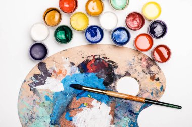 Beyaz arkaplanda Gouache boyaları ve boya fırçası olan paletin üst görünümü