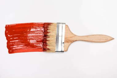 top view of paintbrush near colorful red paint brushstroke on white background clipart