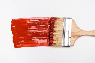 top view of paintbrush near colorful red paint brushstroke on white background clipart
