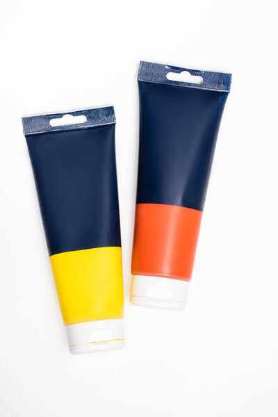 верхний вид красных и желтых труб акриловой краски на белом фоне