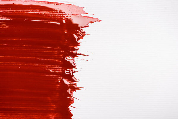 top view of colorful red paint brushstroke on white background
