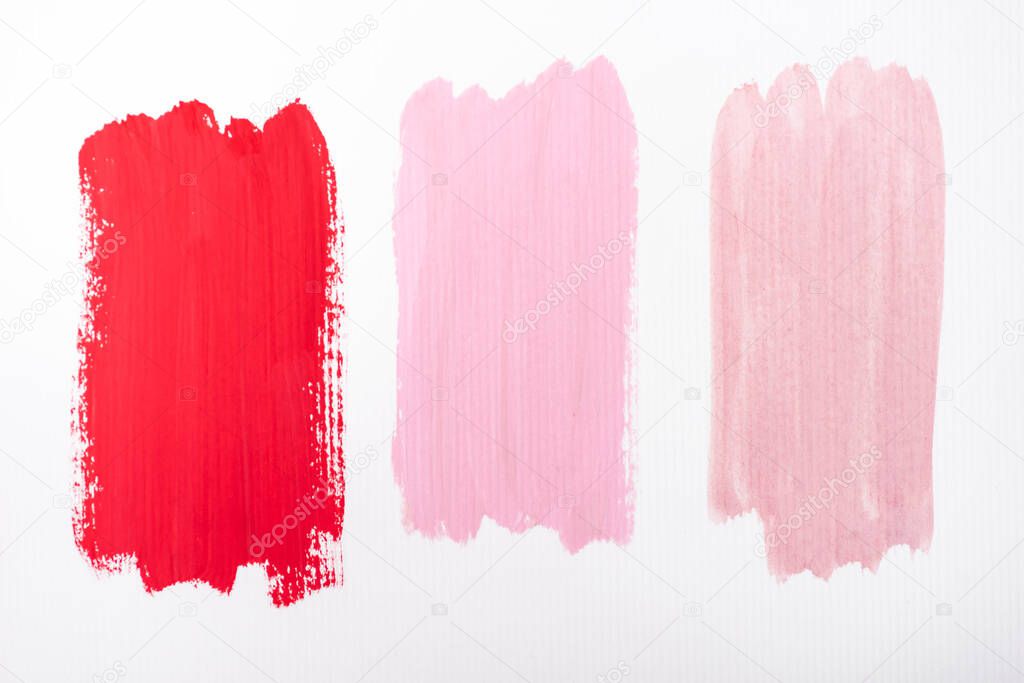 top view of abstract pink and red paint brushstrokes on white background