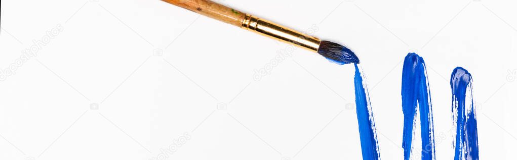 top view of blue paint brushstroke and paintbrush on white background, panoramic shot