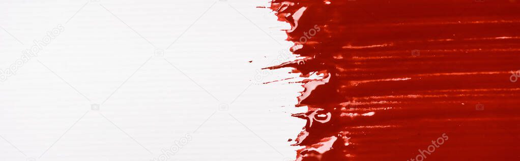 top view of colorful red paint brushstroke on white background