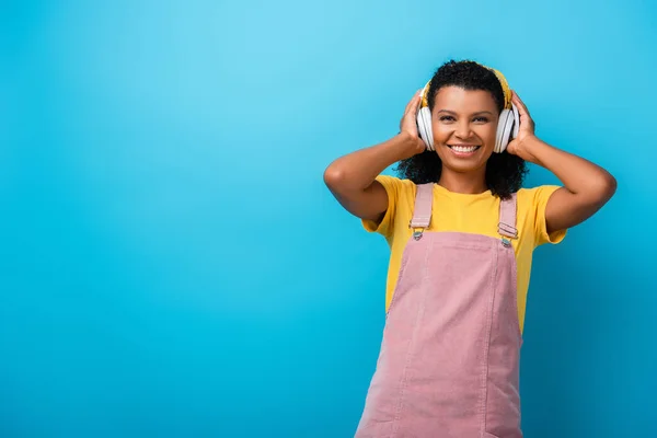 快乐的非洲裔美国女人 戴着无线耳机 用蓝色听音乐 — 图库照片
