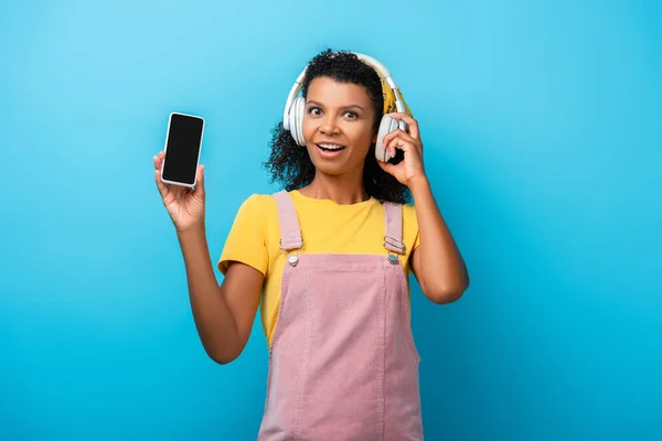 Здивована Афроамериканська Жінка Бездротових Навушниках Слухає Музику Тримає Смартфон Порожнім — стокове фото